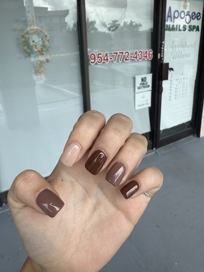 Manicured nails displayed beside polish bottles.